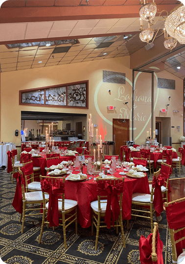 A banquet hall with red linens and gold chairs.