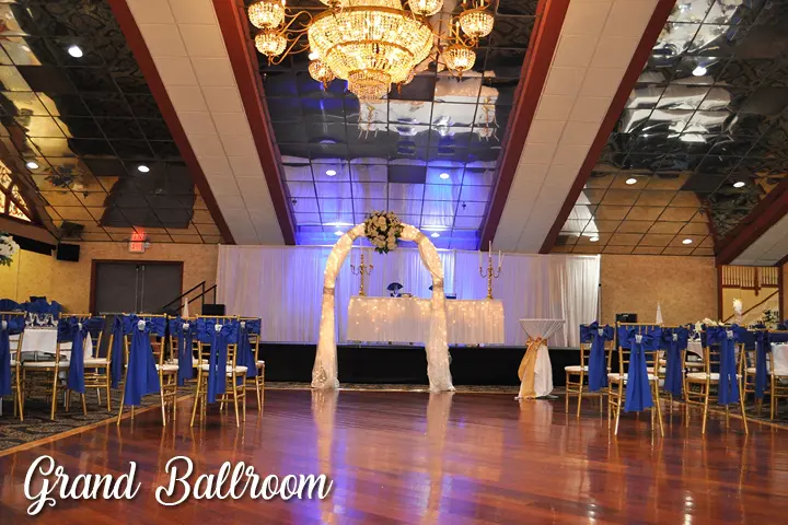 A ballroom with blue chairs and white drapes