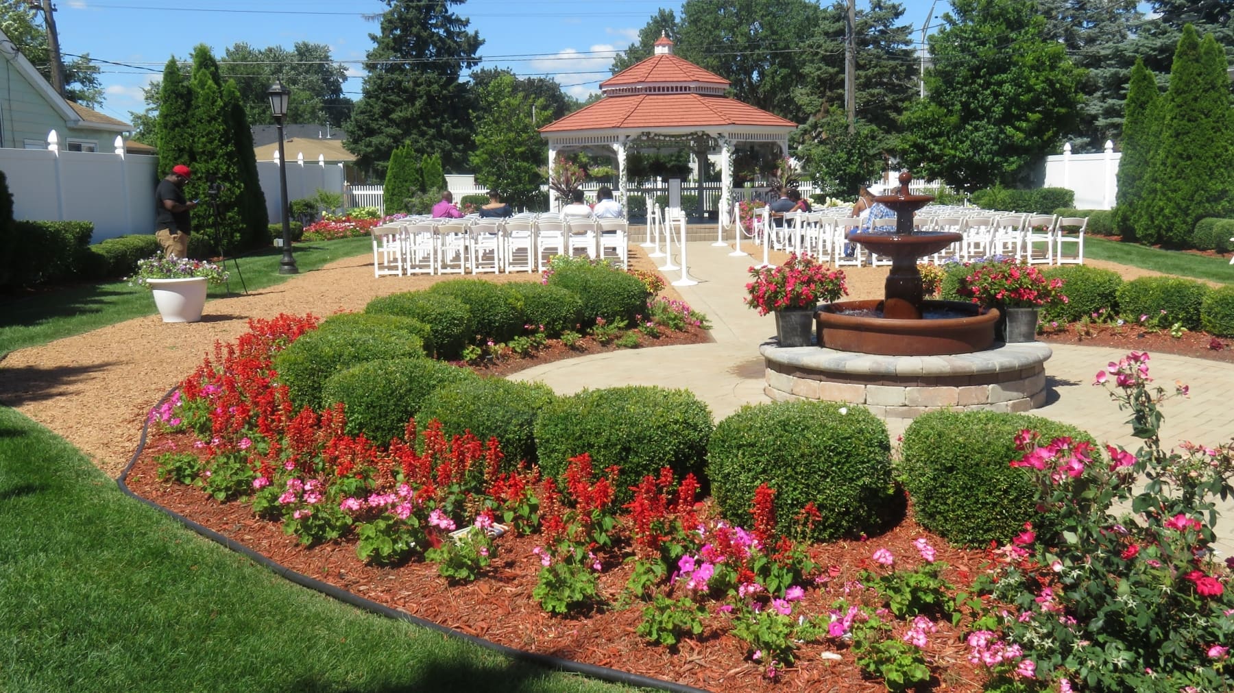 A gazebo with chairs and flowers around it