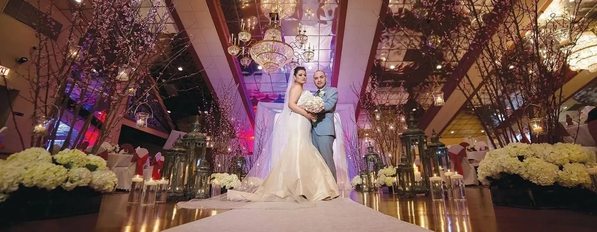 A bride and groom pose for the camera in front of a mirror.