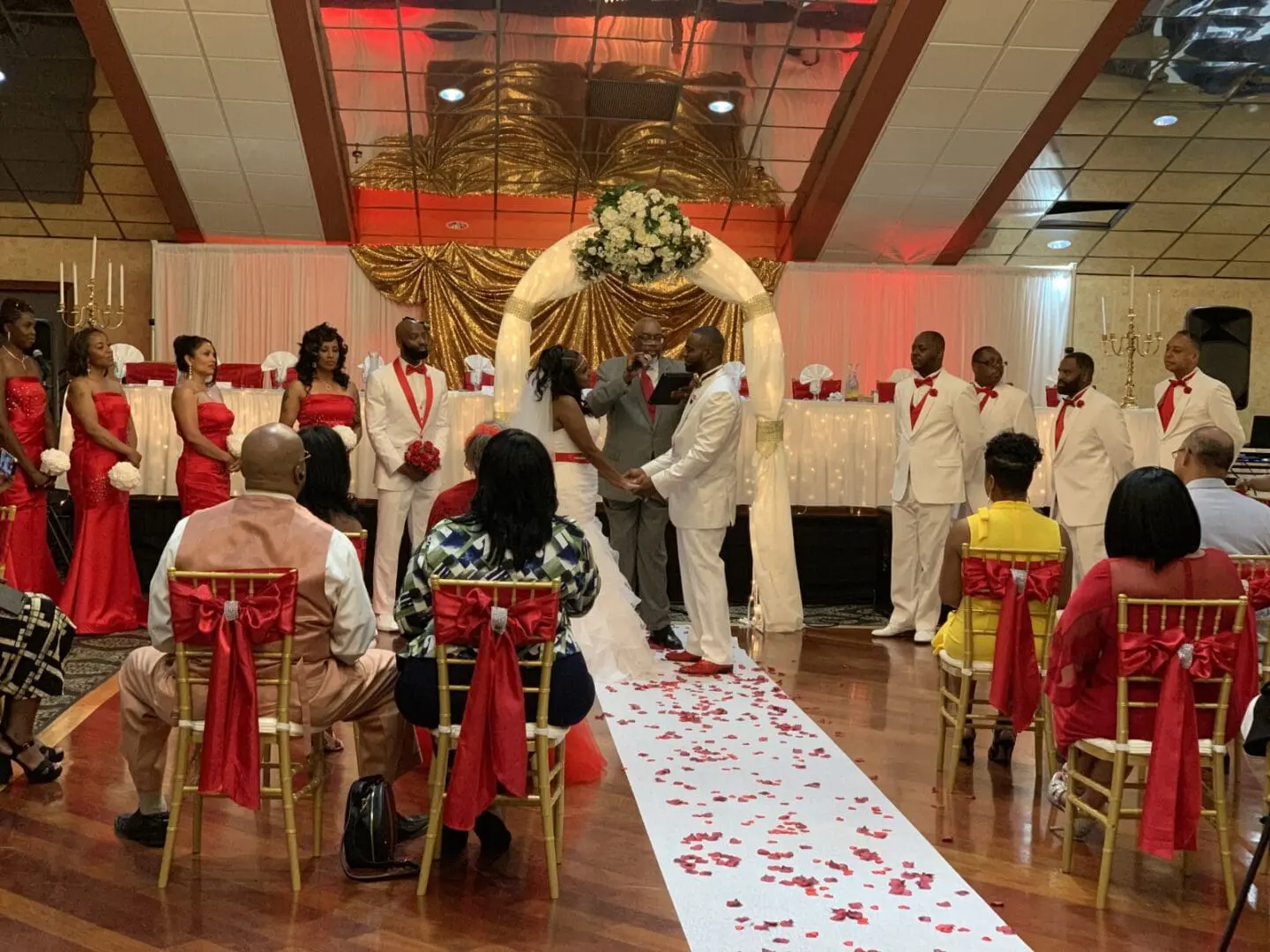 A wedding ceremony with many people in white and red.