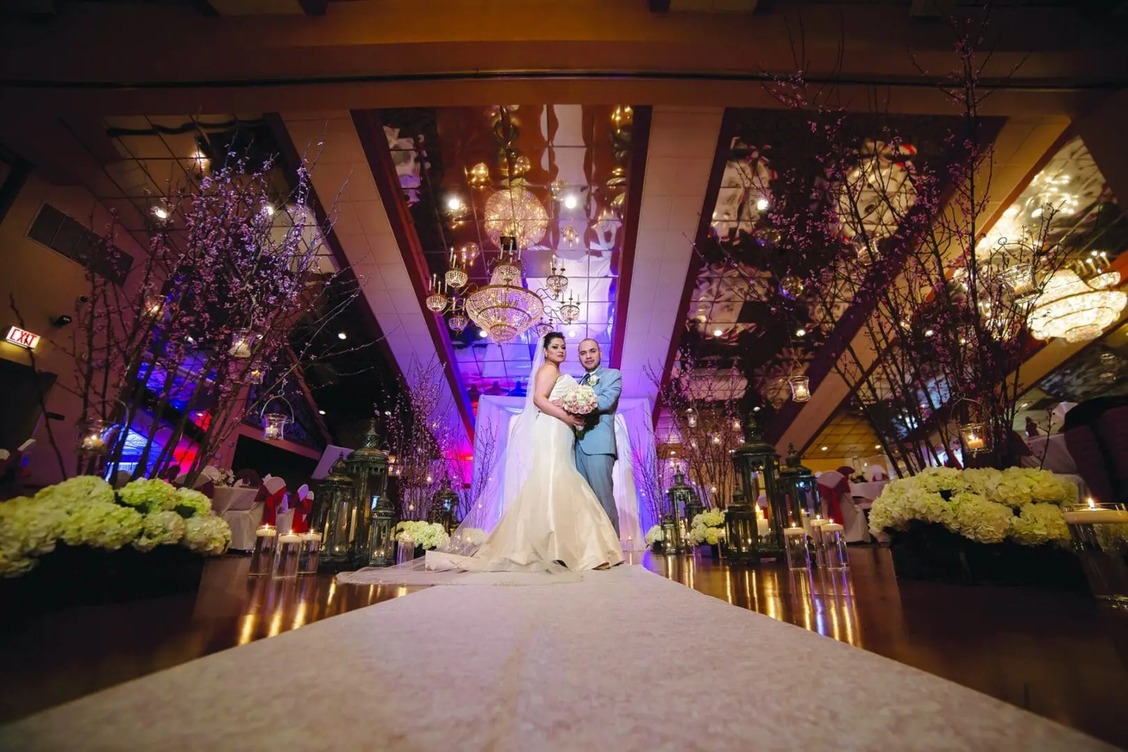 A bride and groom pose for the camera in front of a stage.