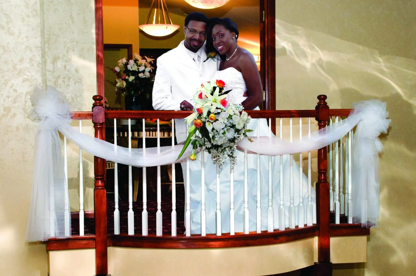 A couple is standing on the balcony of their wedding.