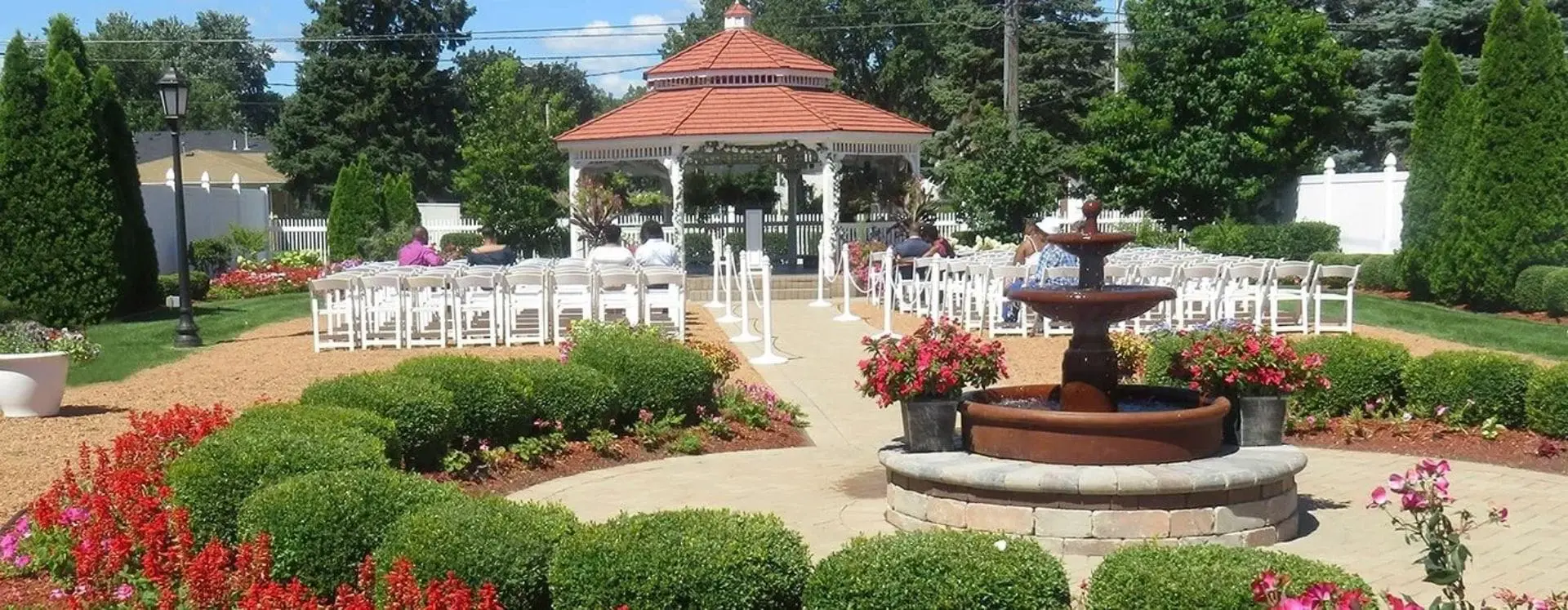 A gazebo with chairs and flowers in the foreground.