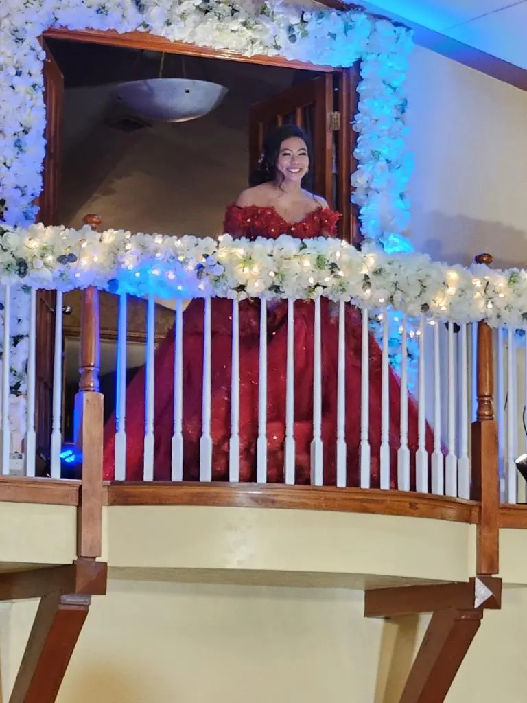 A woman in red dress standing on top of stairs.