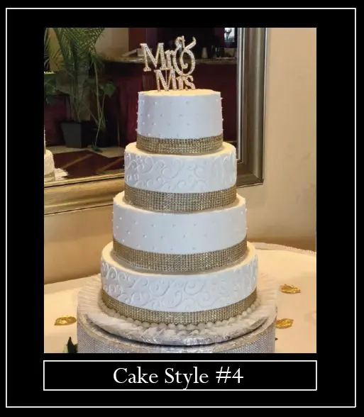 A white wedding cake with gold ribbon and a mr. & mrs. Topper